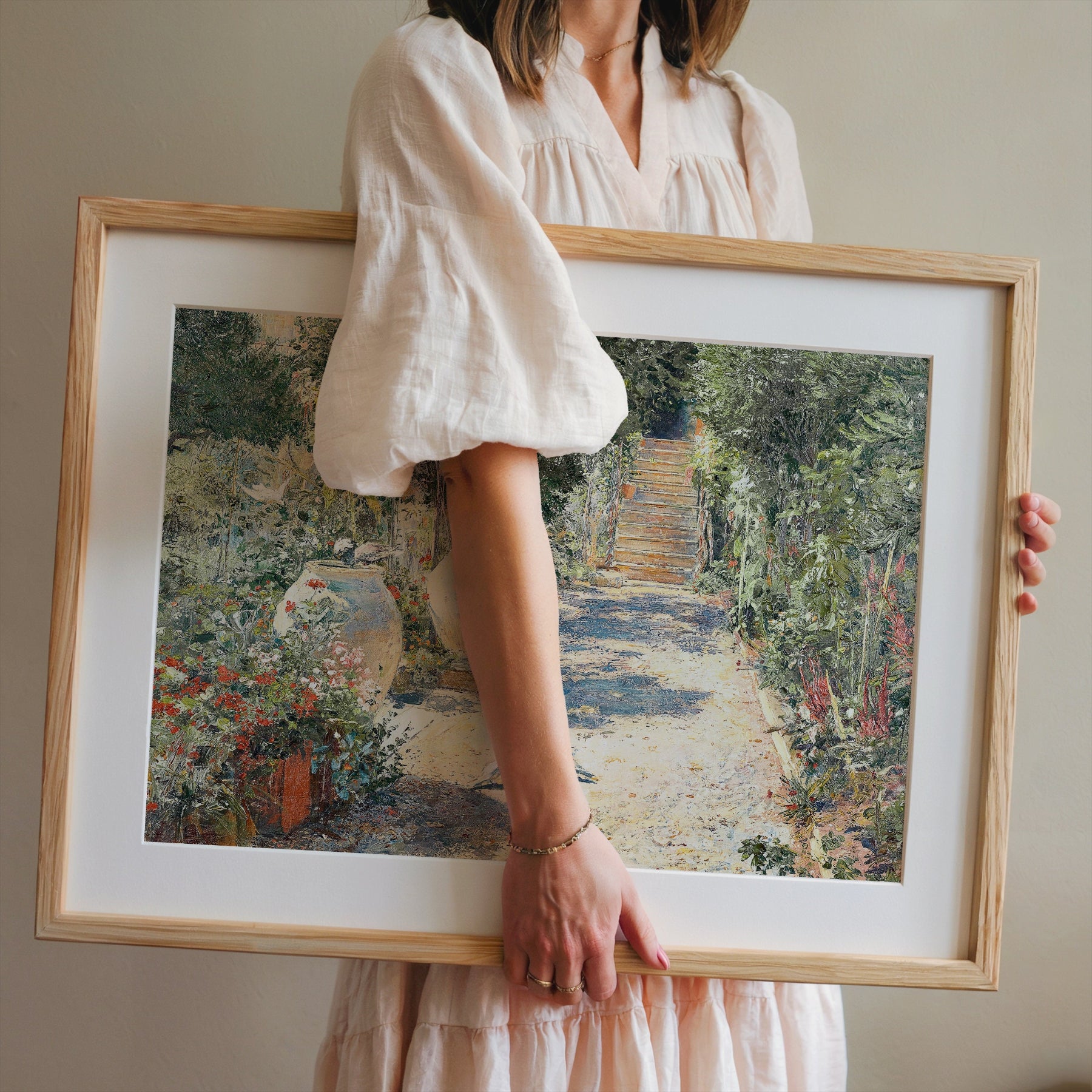 Person holding a framed painting of a garden path